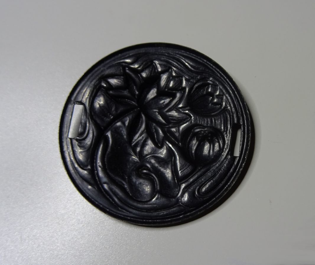 Medalhão de lírio de água em relevo de metal preto com laços laterais 